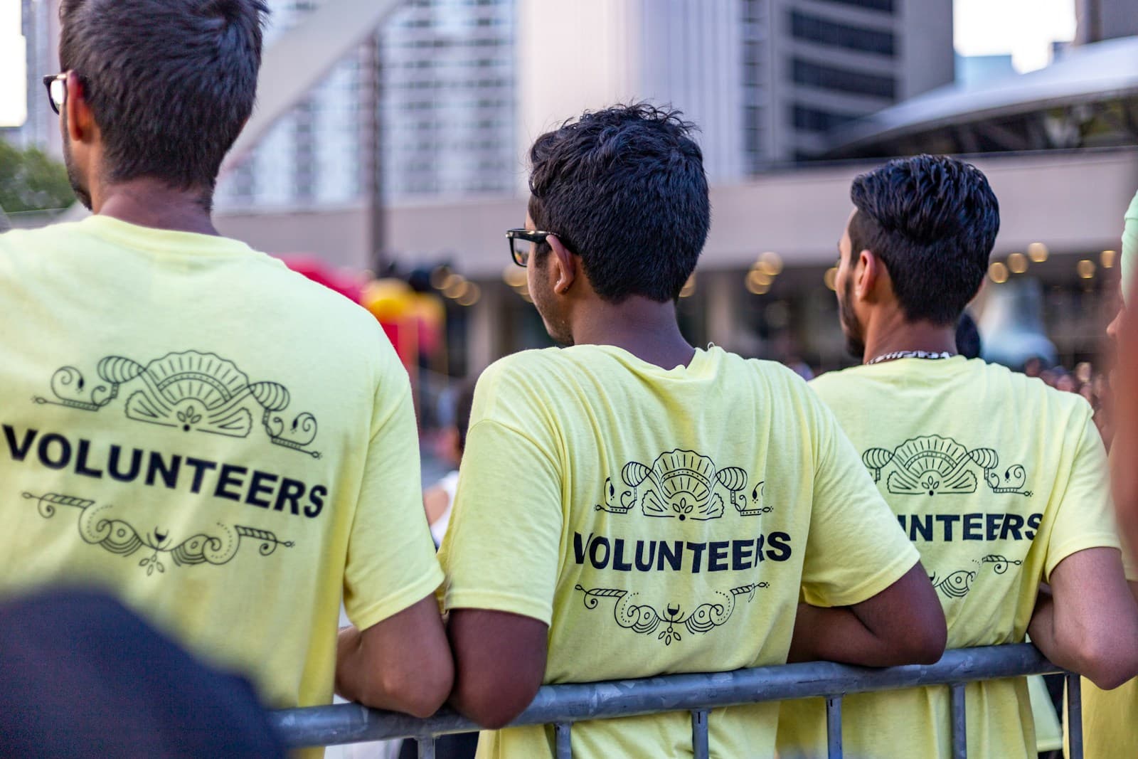 Three volunteers in matching yellow Volunteers shirts at a city event