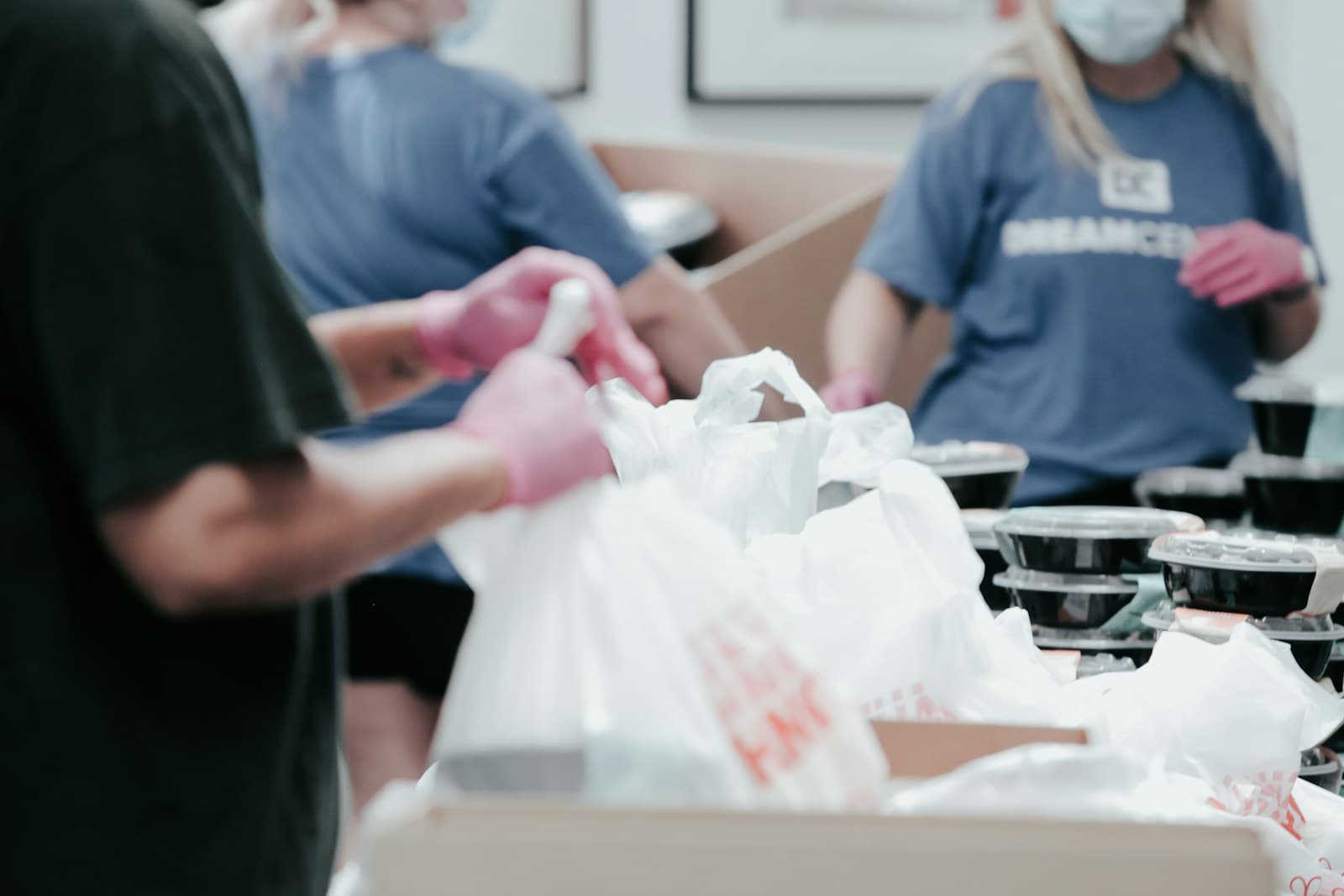 Volunteers packing food into bags at a distribution table